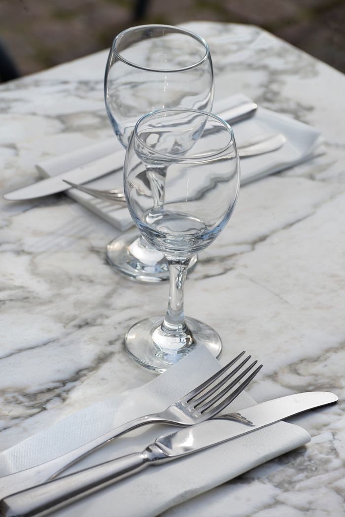 Stylish table setting with wine glasses and silver cutlery on a marble surface, perfect for dining themes.