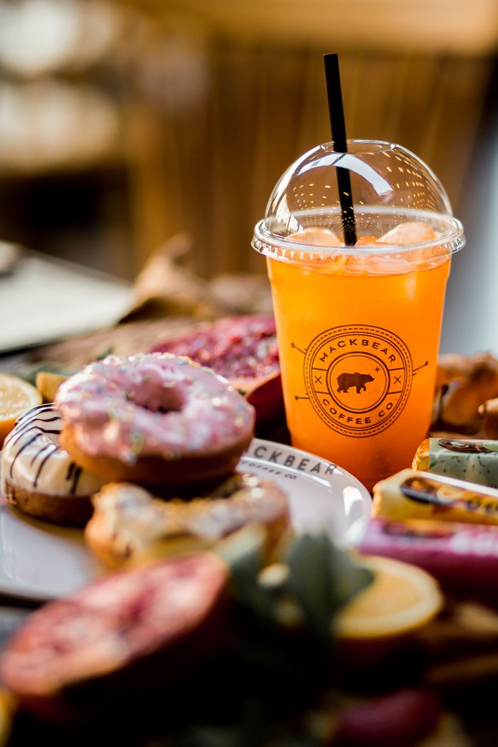 Assortment of colorful donuts with a refreshing orange drink at Hackbear Coffee Co.